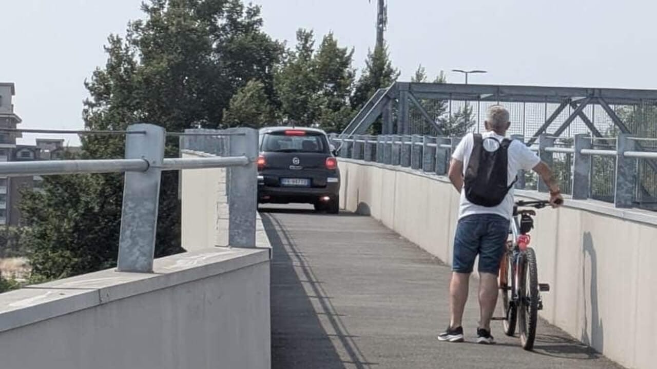 He goes up onto the cycle/pedestrian bridge with his car